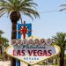 The classic 'Welcome to Las Vegas' sign amidst palm trees, under a bright blue sky.