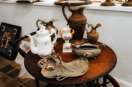 A collection of antique vases and pitchers artfully arranged on a vintage table indoors.