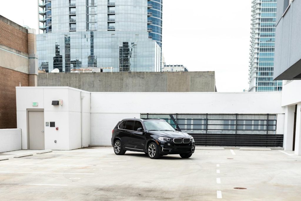 Black luxury SUV parked in a city rooftop lot with modern buildings in background.