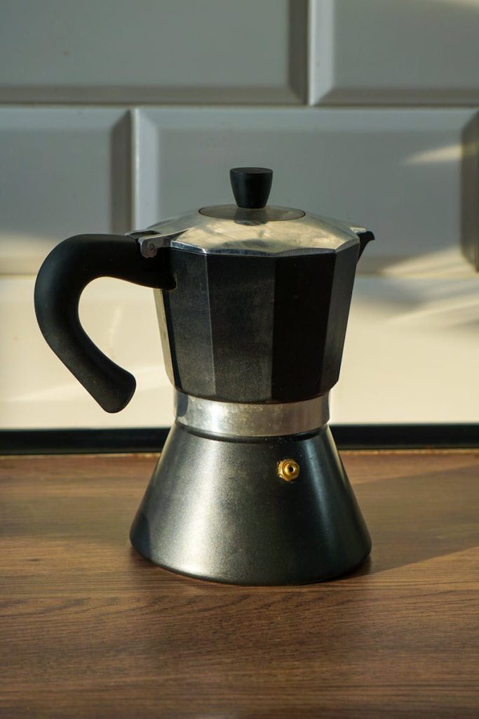 Close-up of a classic moka pot coffee maker in natural light on a kitchen countertop.