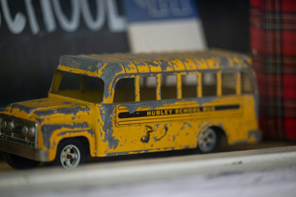 Close-up of a vintage toy school bus in yellow with a distressed finish.