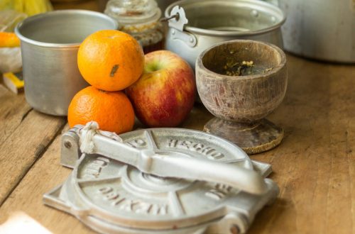 stack of orange and apples by pots on table top